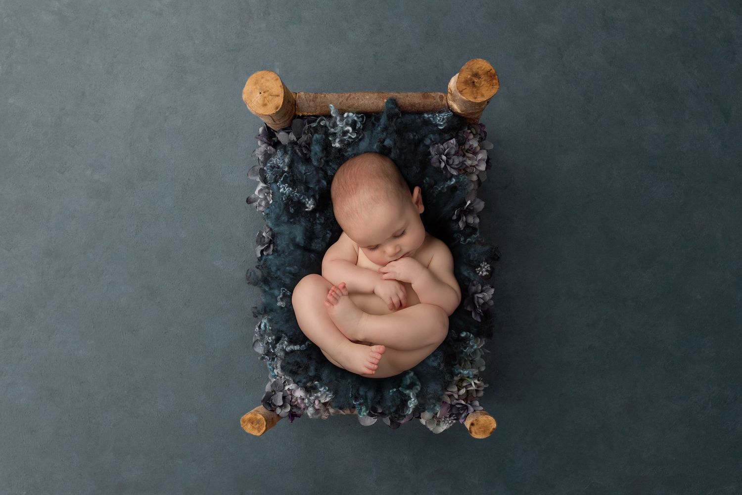 Baby resting in blue textured setting with glowing orange decorative elements.