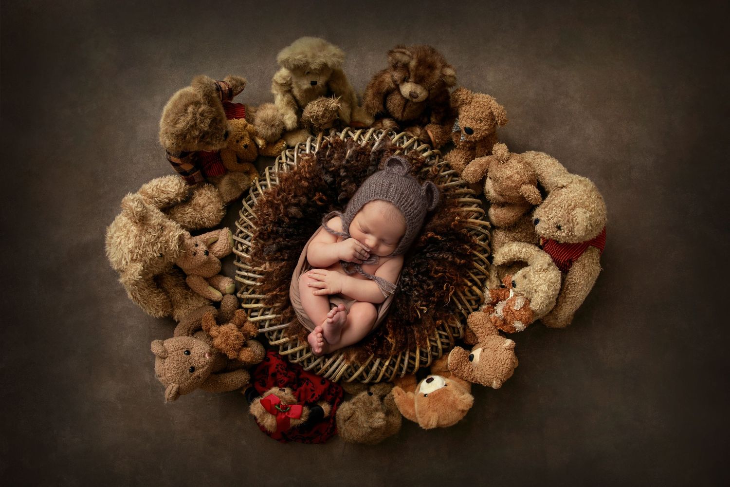 Creative newborn portrait with baby sleeping in woven basket surrounded by teddy bears.