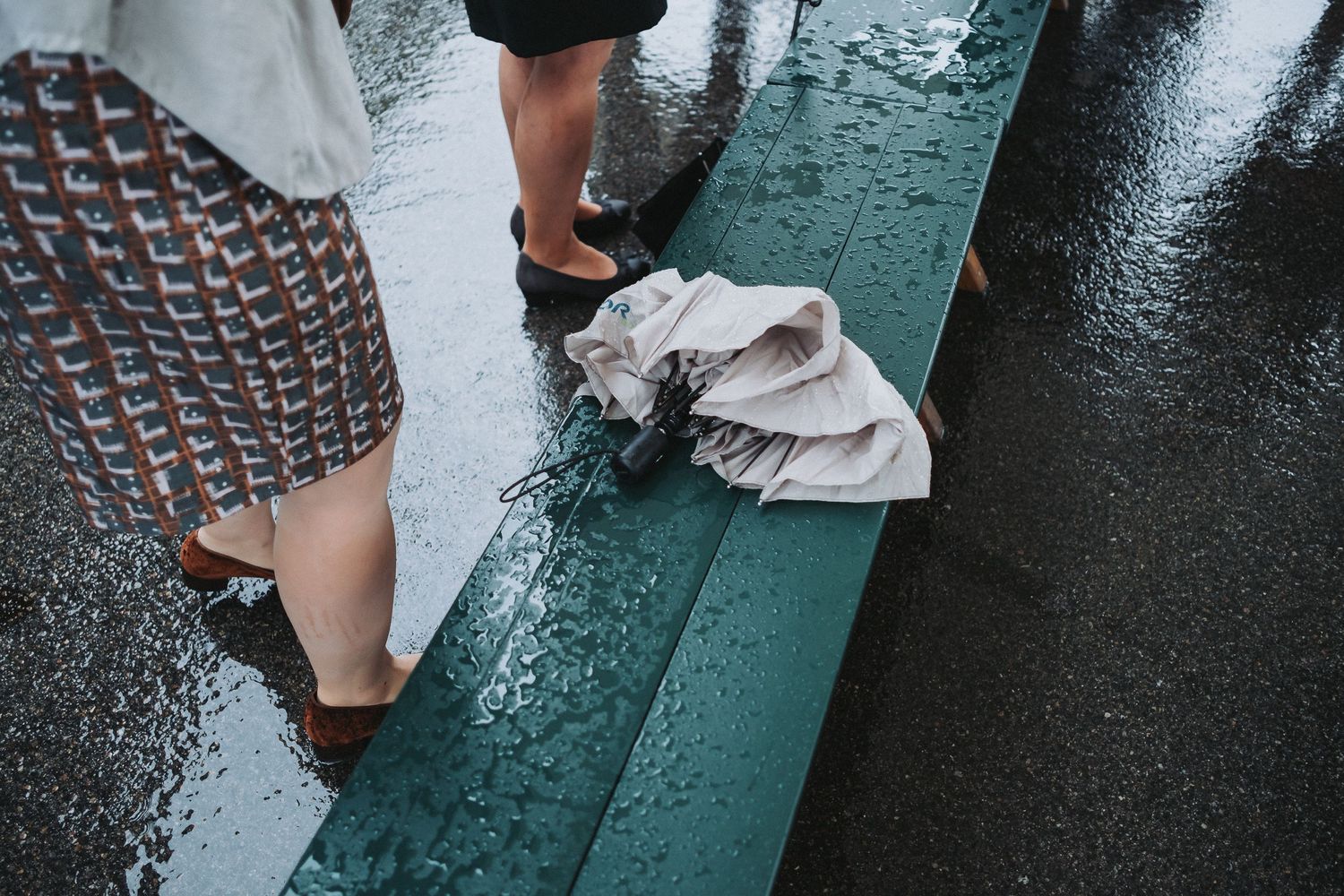 Feet and legs walking on wet pavement during rainy weather.