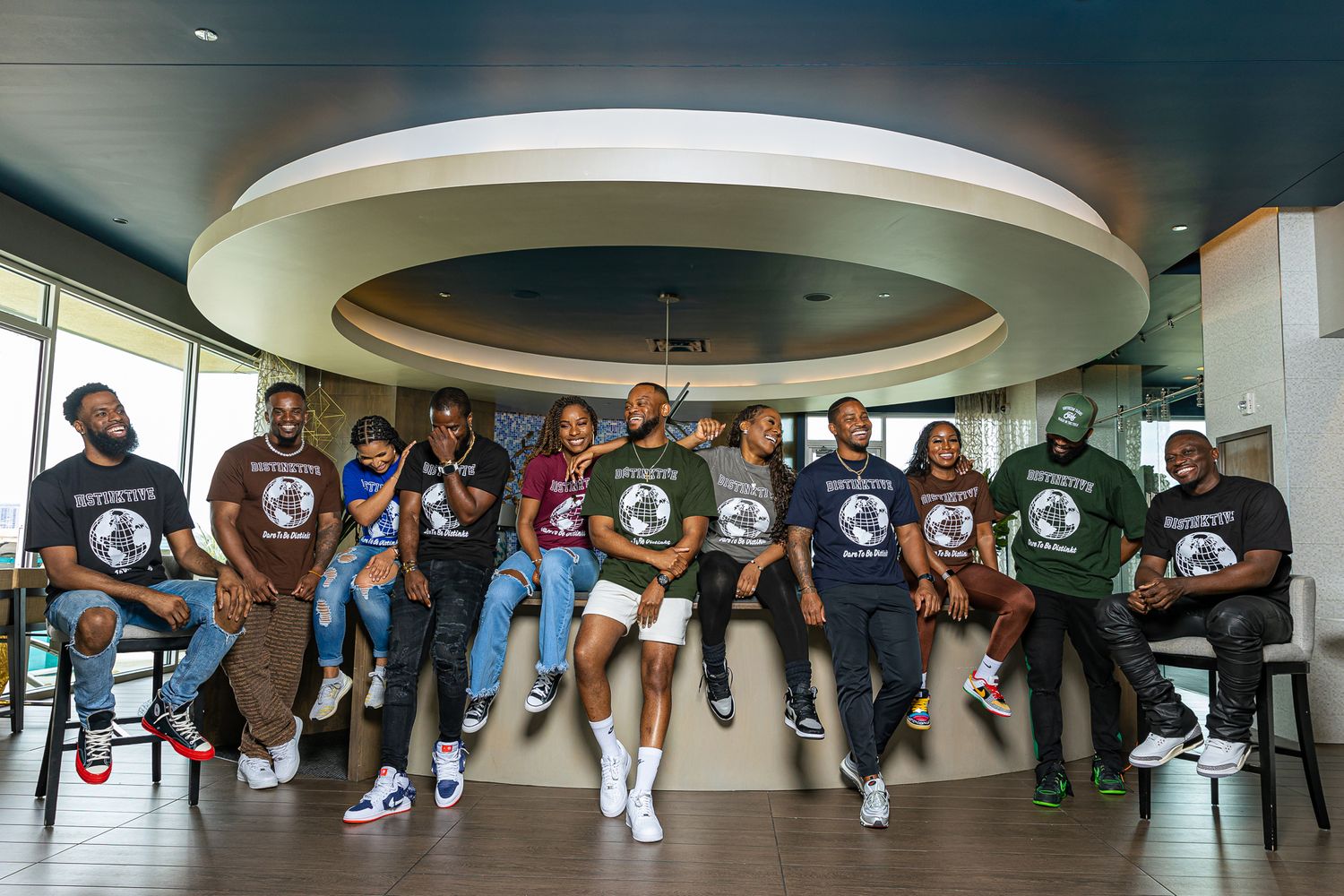 Group photo of people wearing matching t-shirts sitting on a circular bench under a round ceiling.