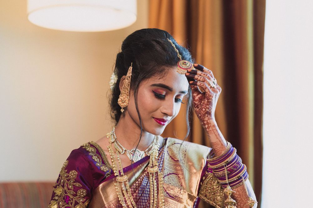 Traditional Indian bridal preparation with intricate jewelry and burgundy attire.