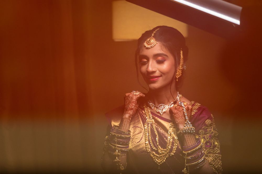 Artistic portrait of bride in traditional attire with warm lighting and reflective effects.