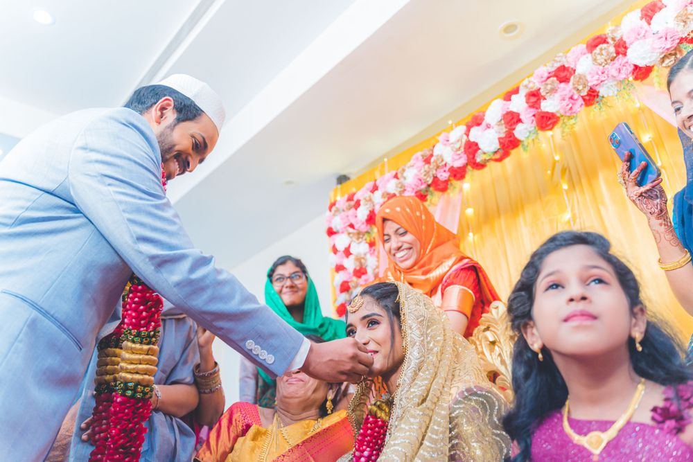 Cultural ceremony showing exchange of ceremonial items with decorative backdrop.