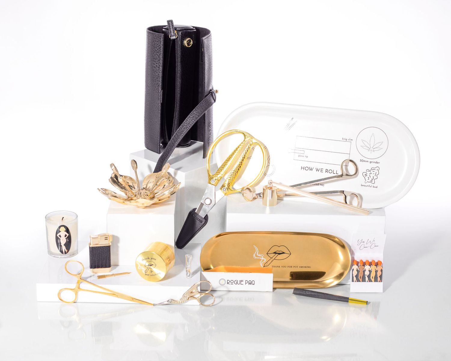 Luxury gold and black cannabis accessories collection including scissors, case, and tools on white background.