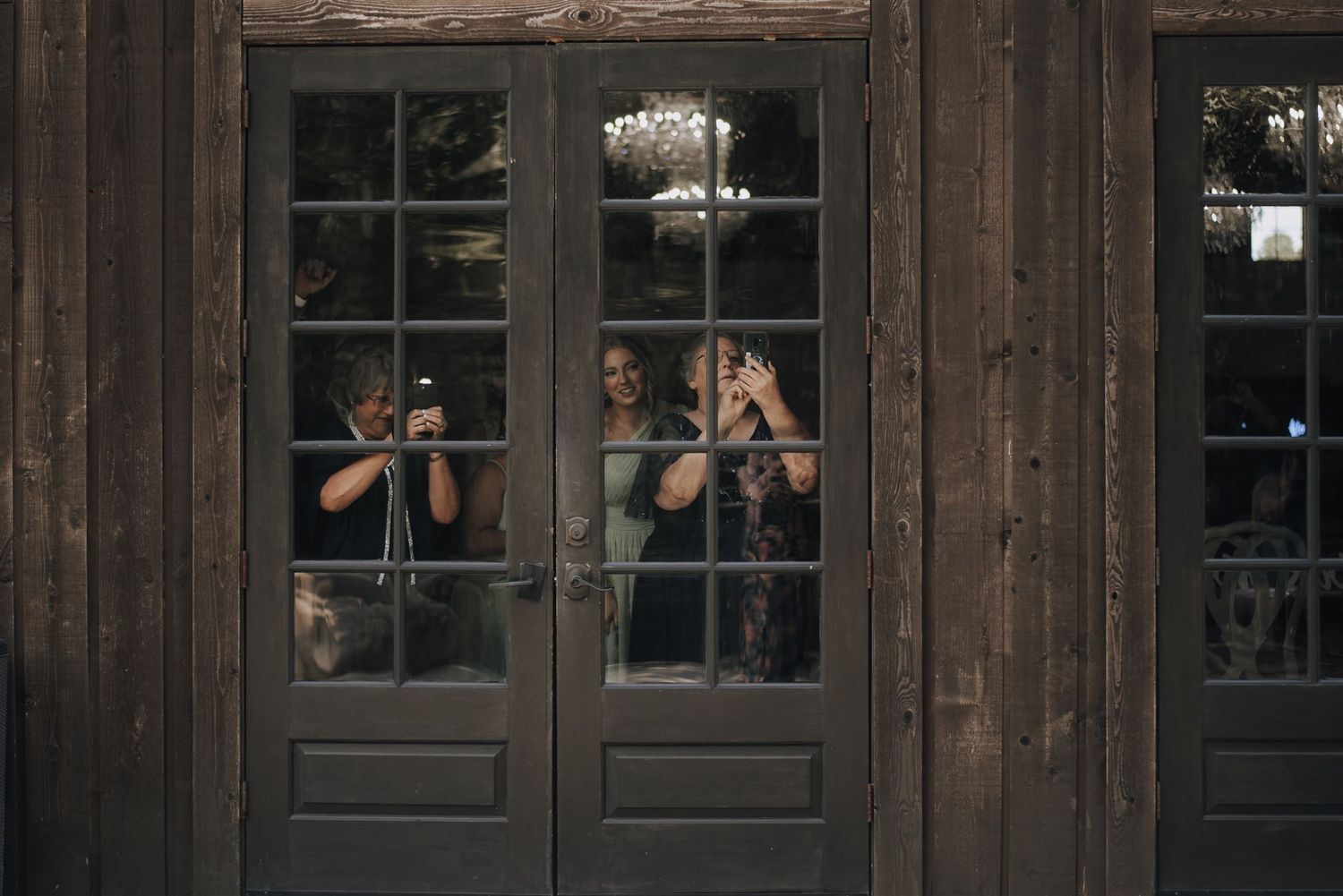 Reflection through vintage wooden doors of people taking photos.