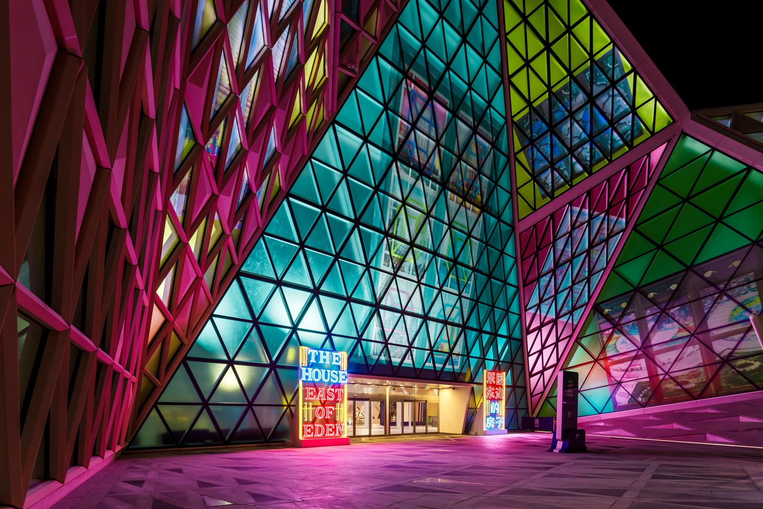 A modern architectural space features vibrant triangular patterns and illuminated signage.