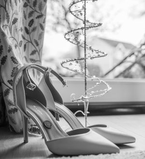 Wedding shoes displayed artistically with decorative spiral lights in background.