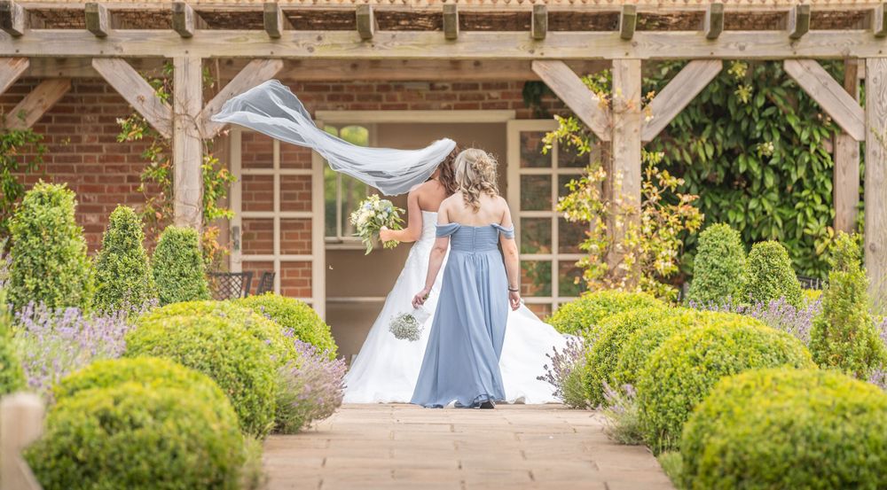 Wedding couple portraits taken in a garden setting with brick architecture.