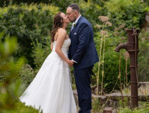 Romantic garden wedding portraits among natural greenery and rustic elements.