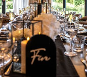 Elegant table settings at a wedding reception with dark tablecloths and wine glasses.