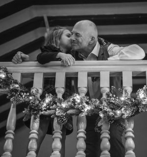 Romantic couple sharing intimate moments through decorative white balustrade with flowers.