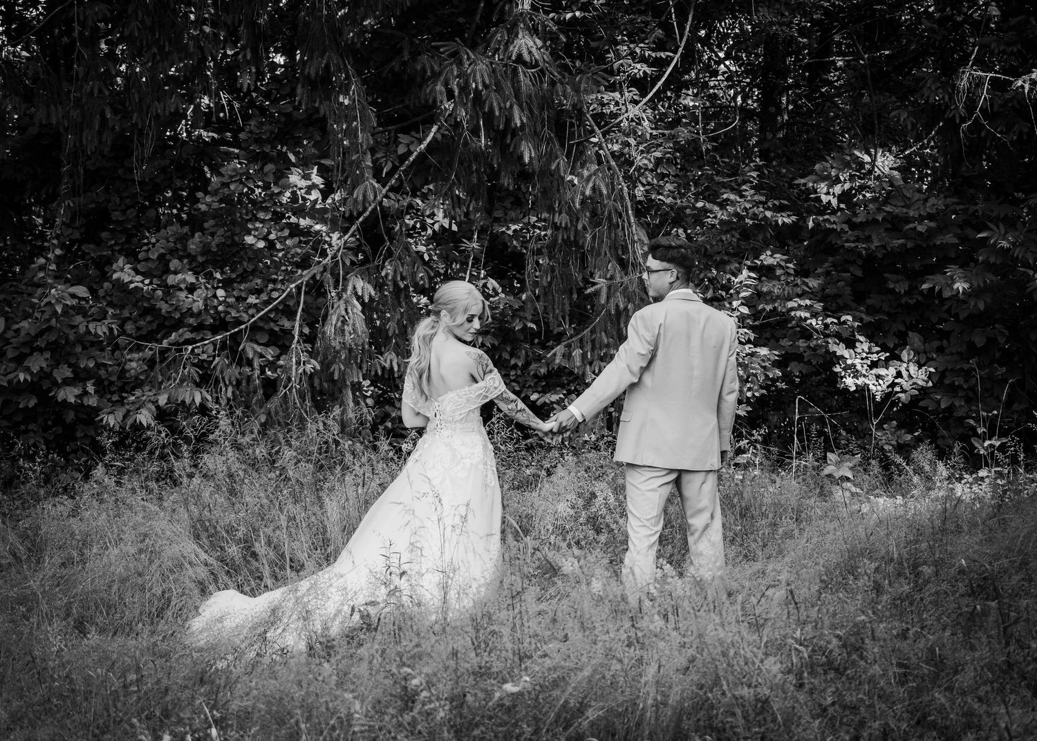 bride and groom walking through tall grass area