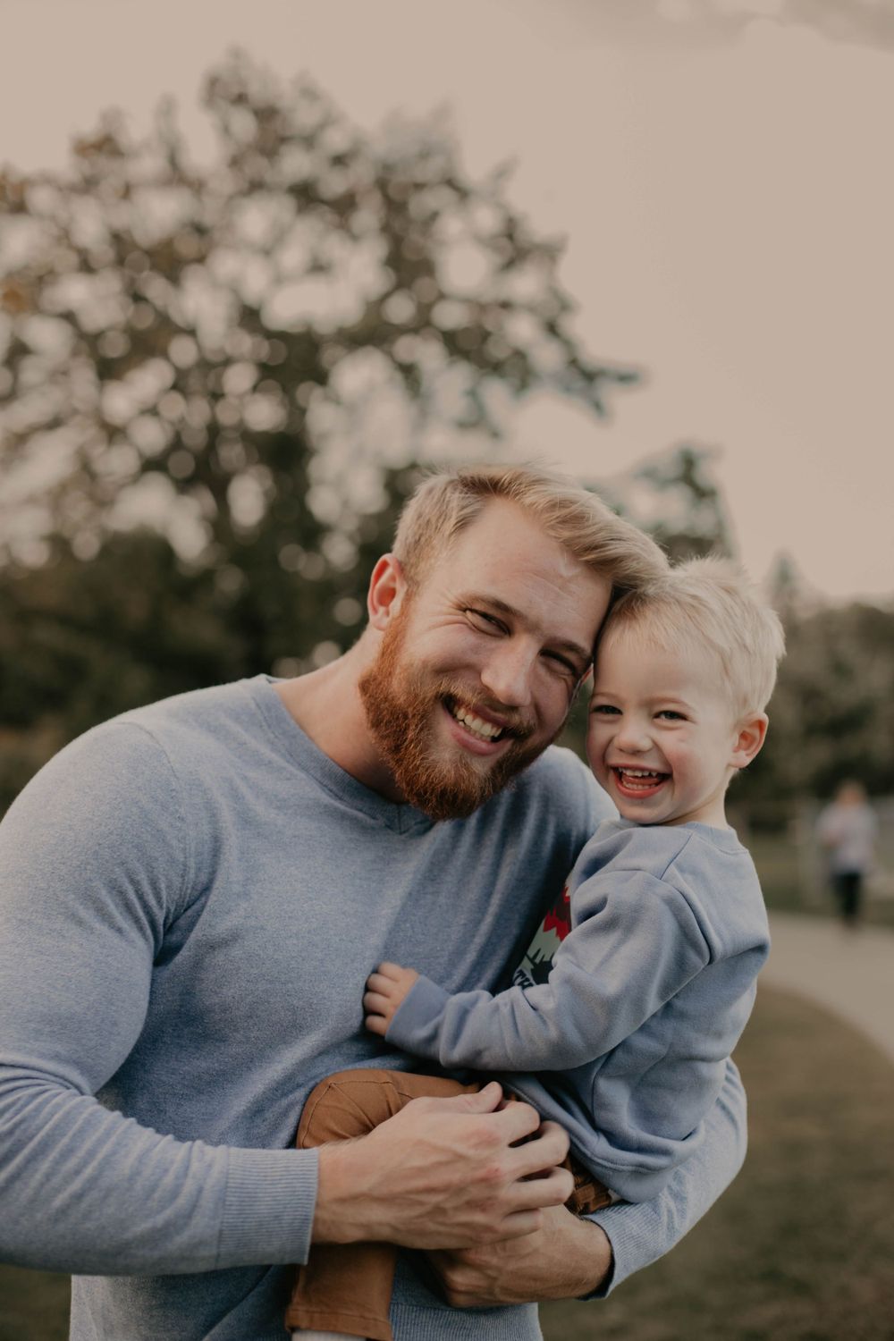 Heartwarming candid moment between parent and child laughing together outdoors.