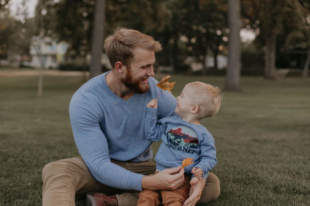 Sweet bonding moment between parent and child sitting on grass in a park setting.