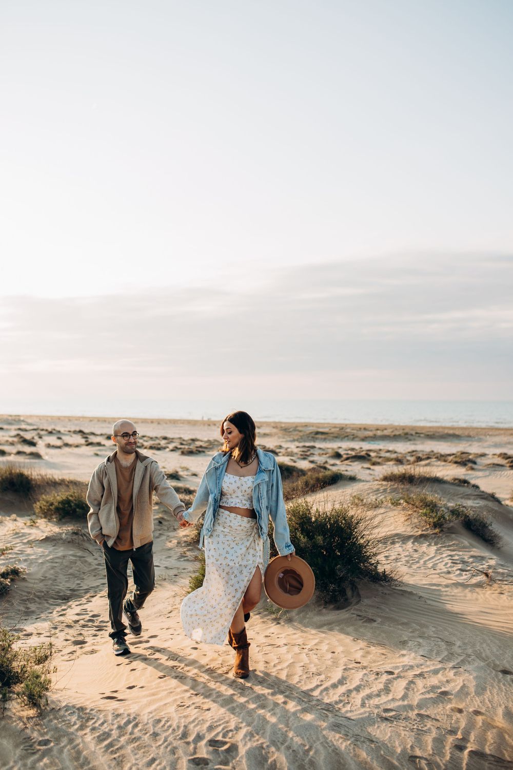 A stylish couple explores desert landscape with a straw hat and denim jacket.