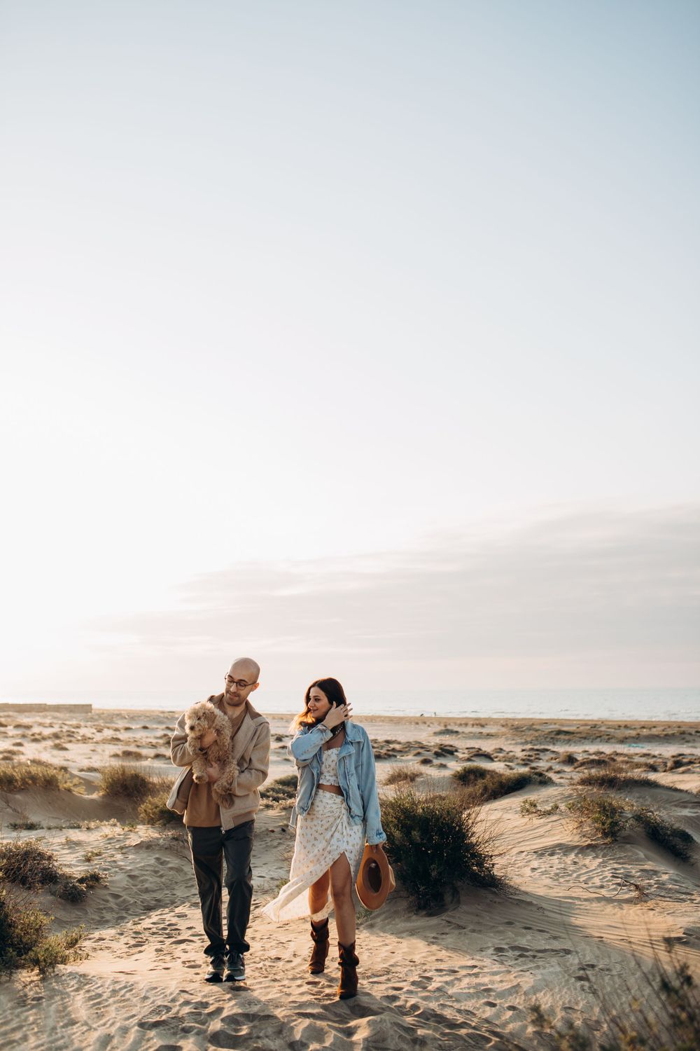 A couple shares a tender moment while exploring desert dunes at sunset.