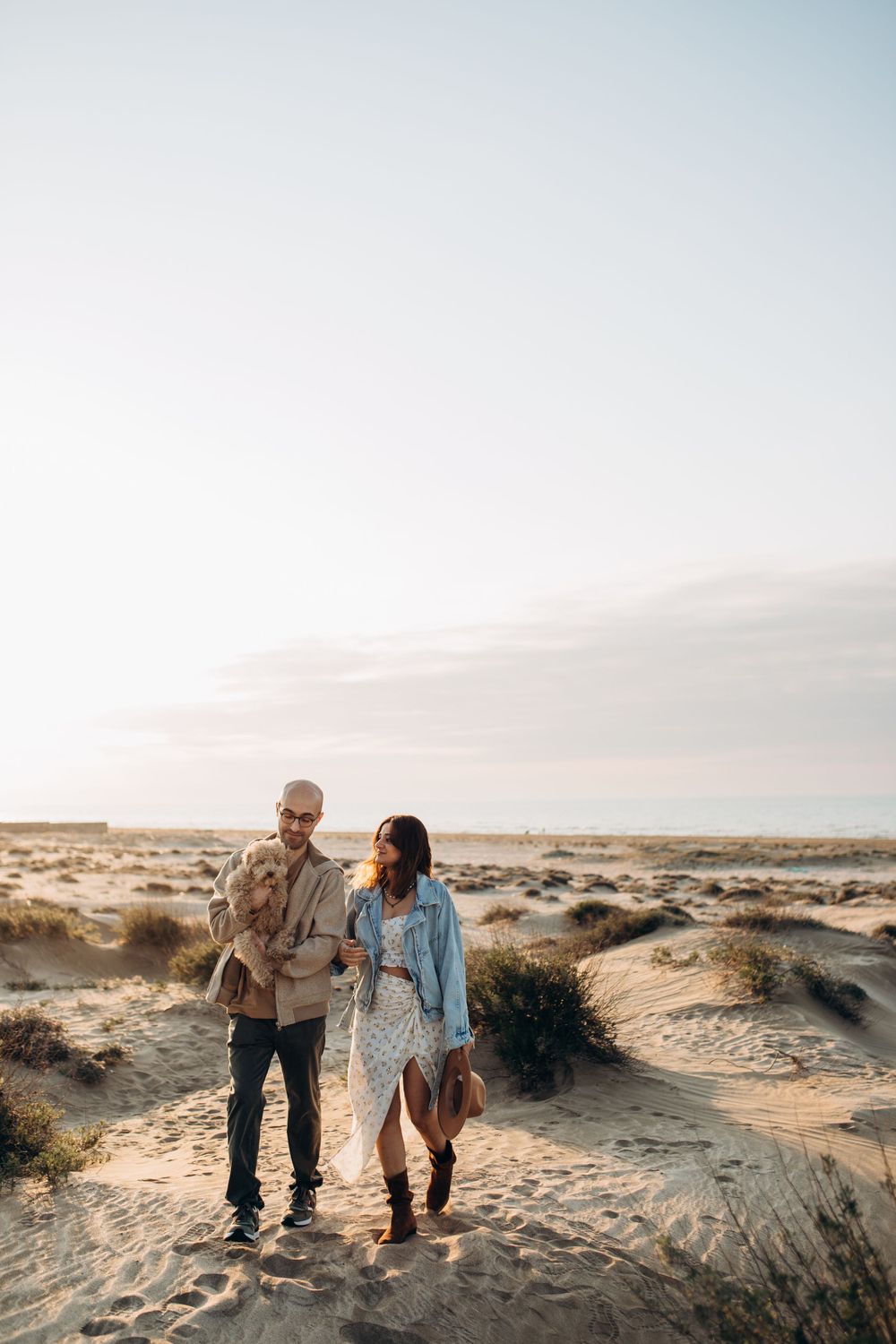 A couple walks together through desert terrain during golden hour.