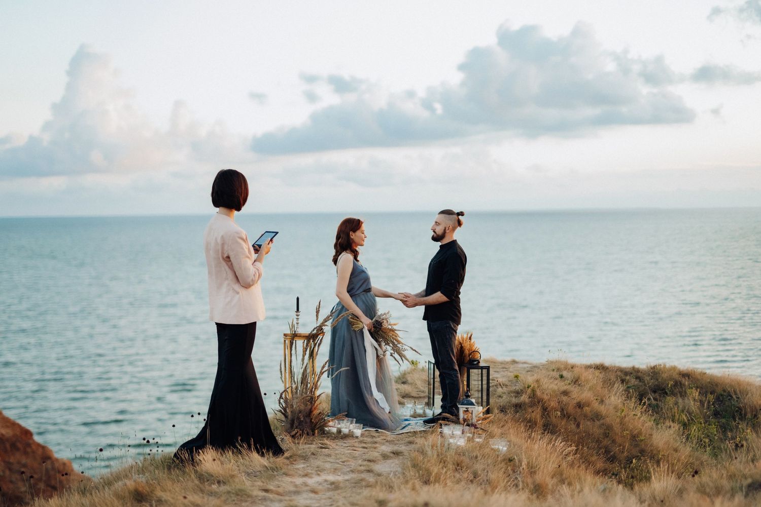Couple embracing on a scenic coastal cliff at sunset.