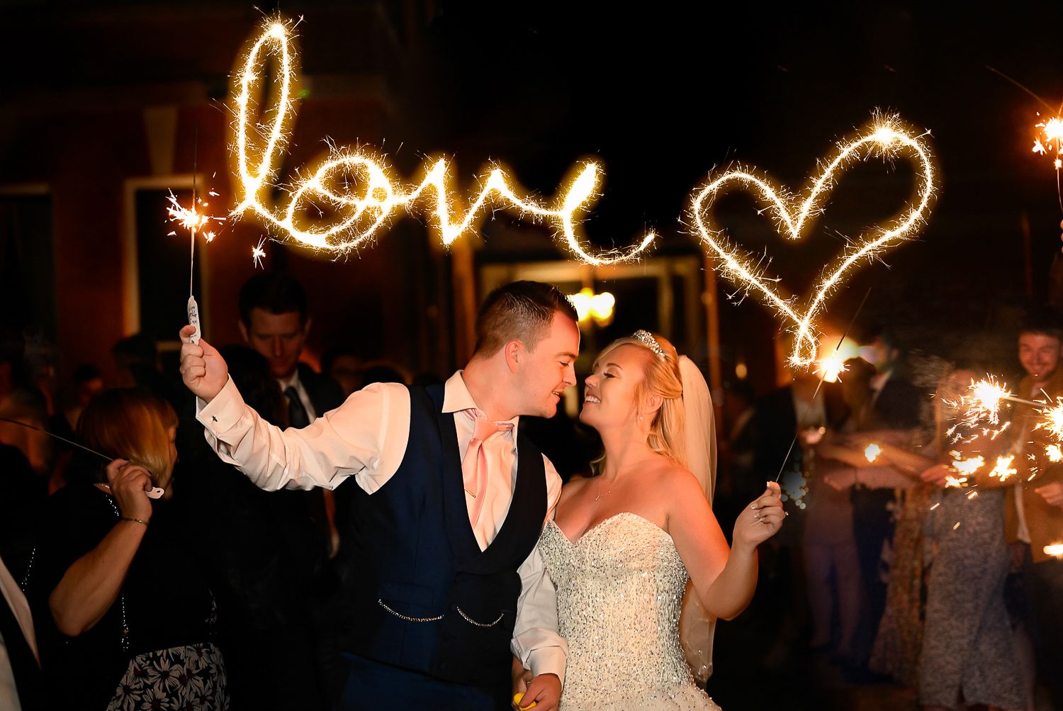 Wedding sparkler exit with 'love' written in light against dark night sky.