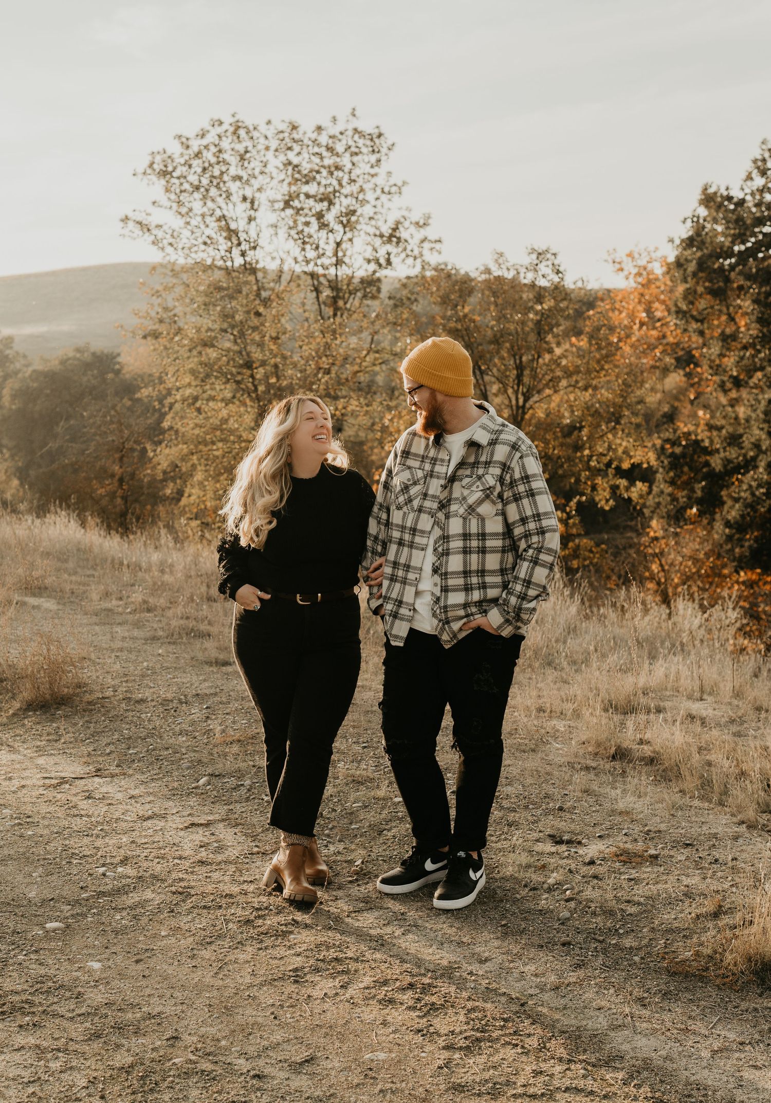 Couple walking together on autumn trail wearing casual attire.