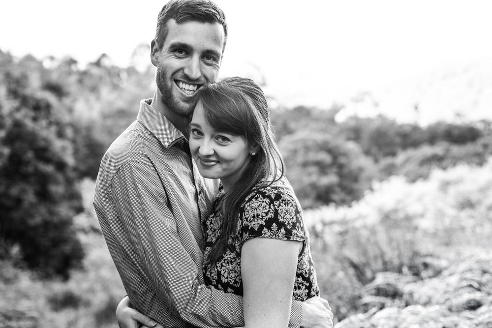 Black and white portrait of a couple embracing outdoors during their engagement session.