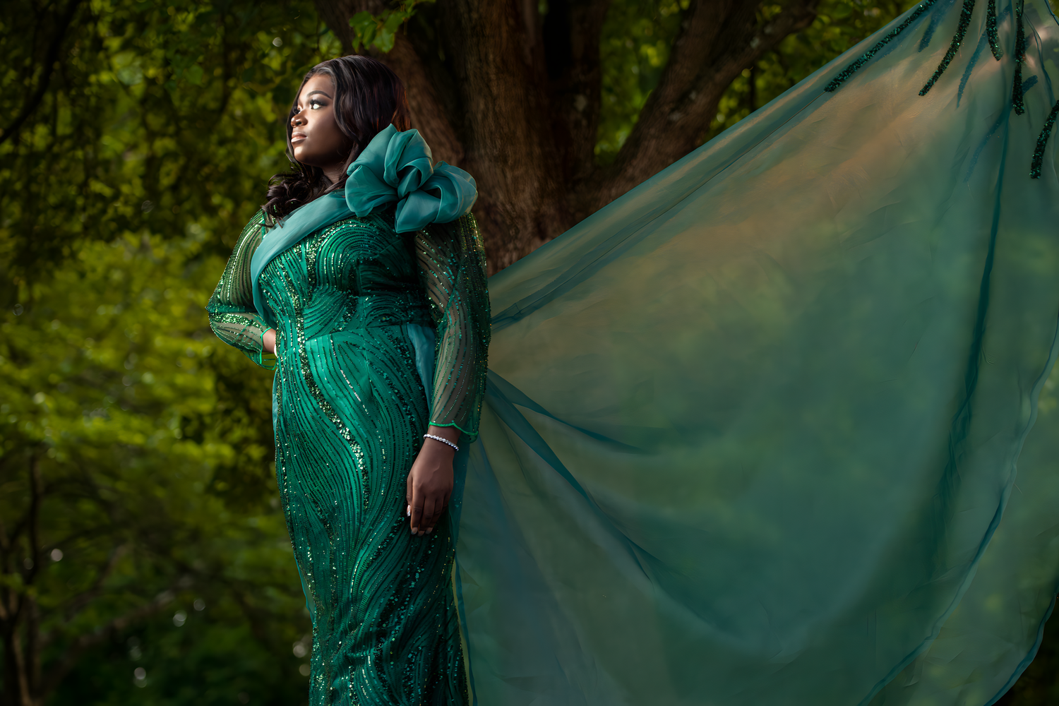 Flowing emerald green dress photoshoot in a lush forest setting.