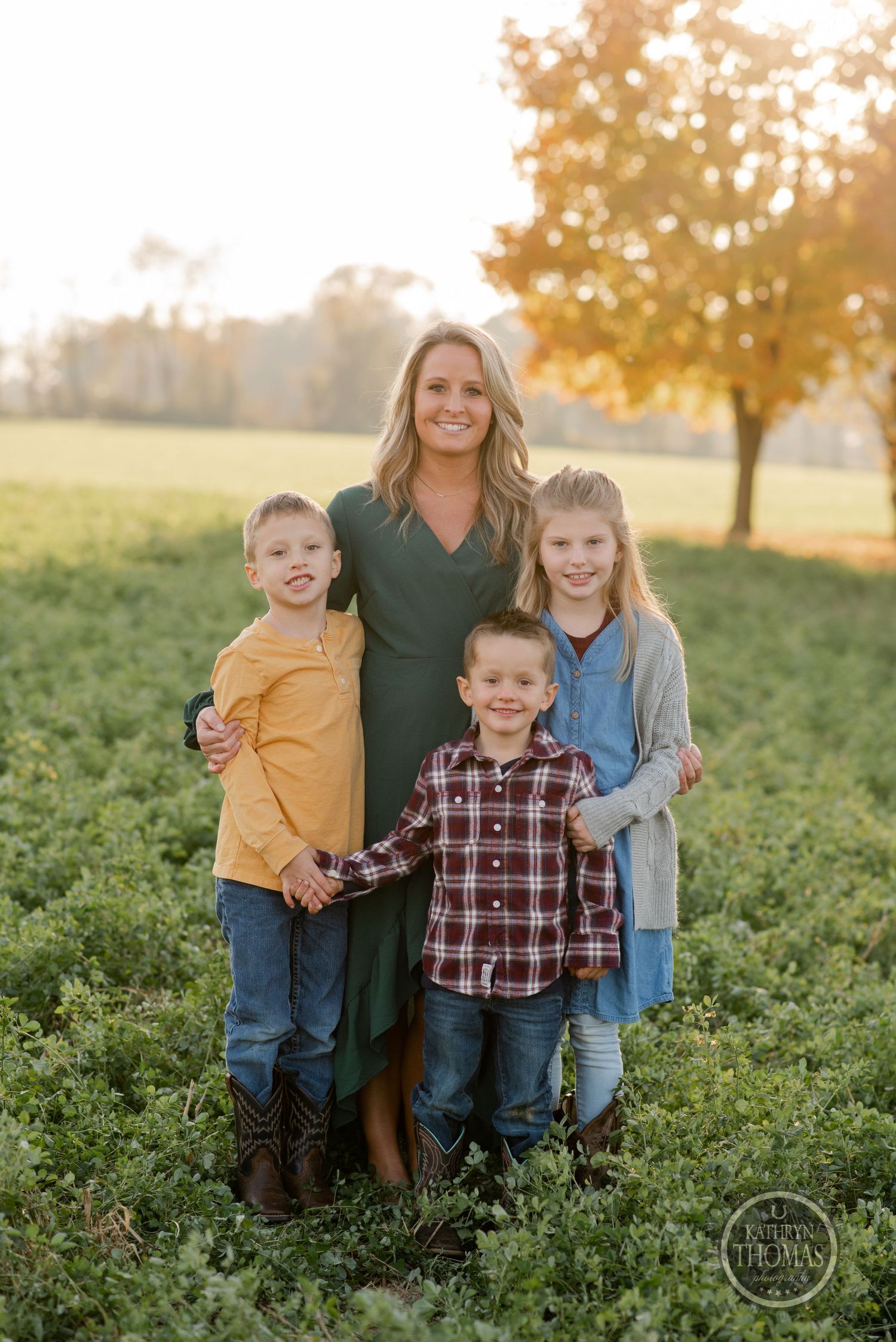 Family portrait of a group standing together in a lush green field during golden sunset.