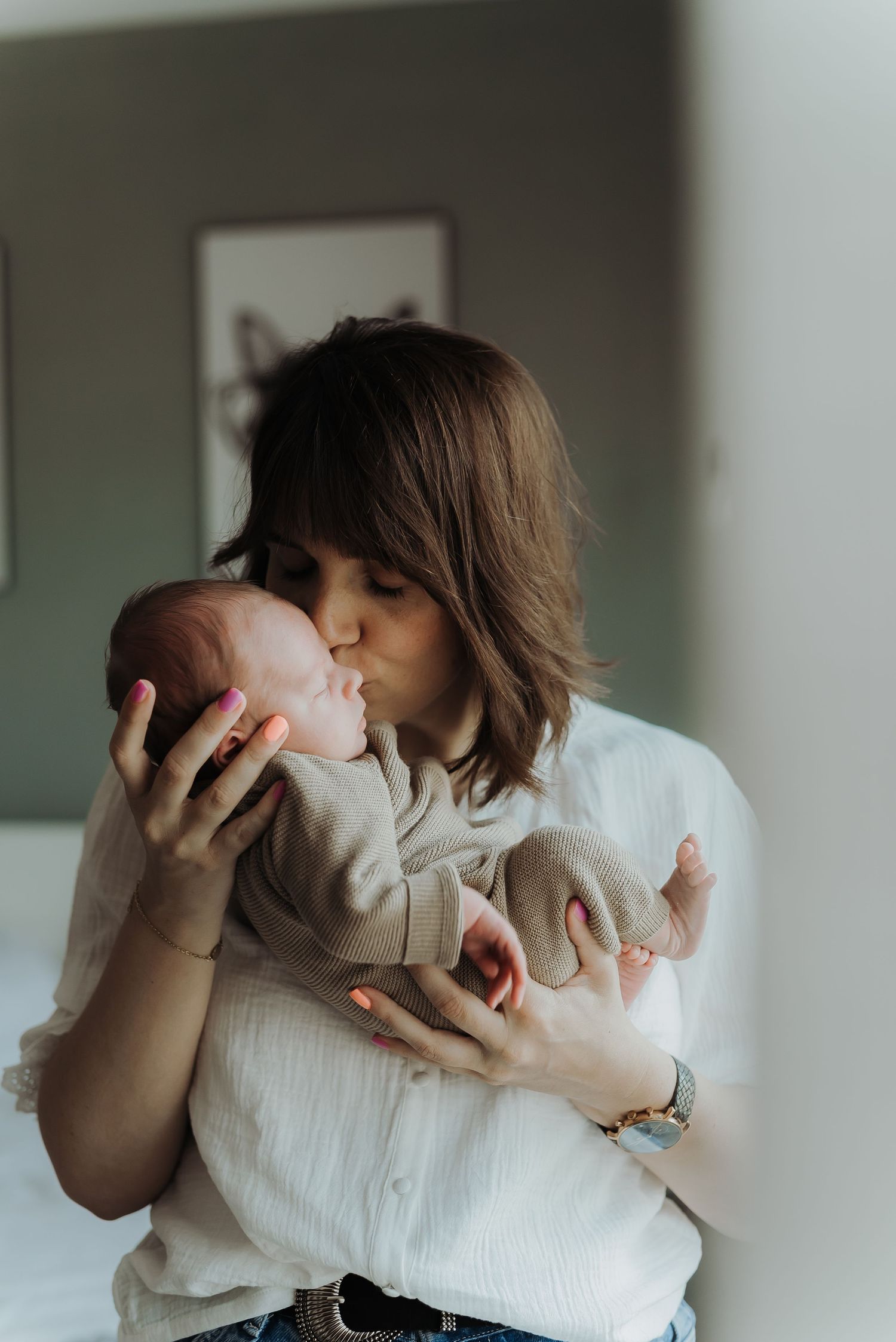 Tender moment between parent and newborn baby in white clothing.