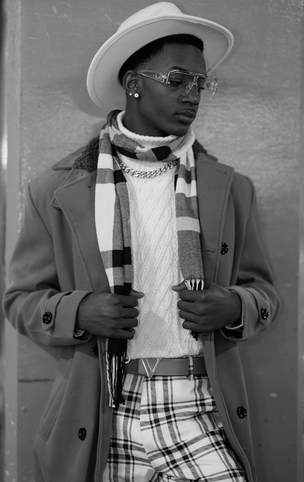 High-contrast black and white portrait of a man, showcasing his fashion and style.