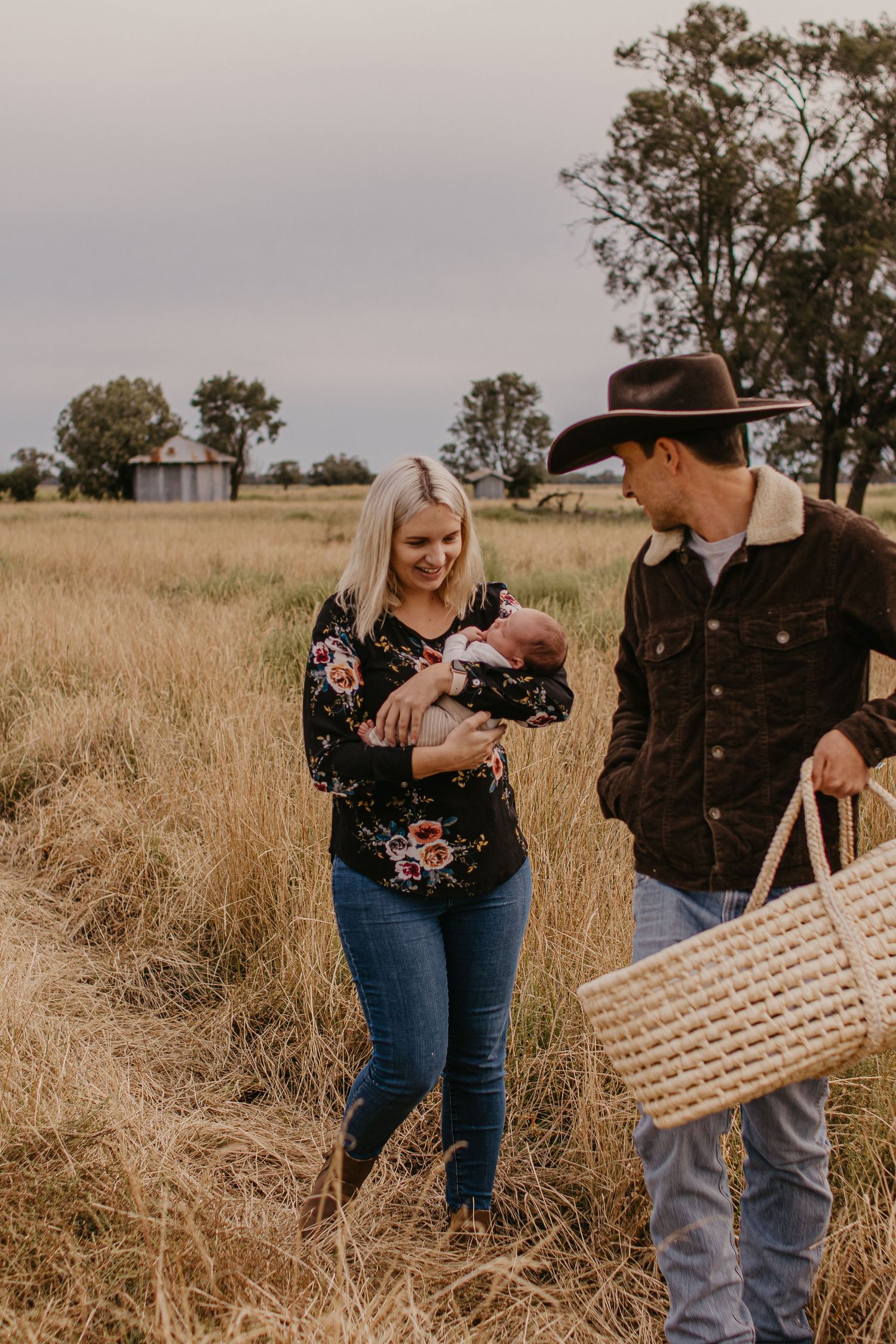 Rural parents in a paddock holding newborn baby