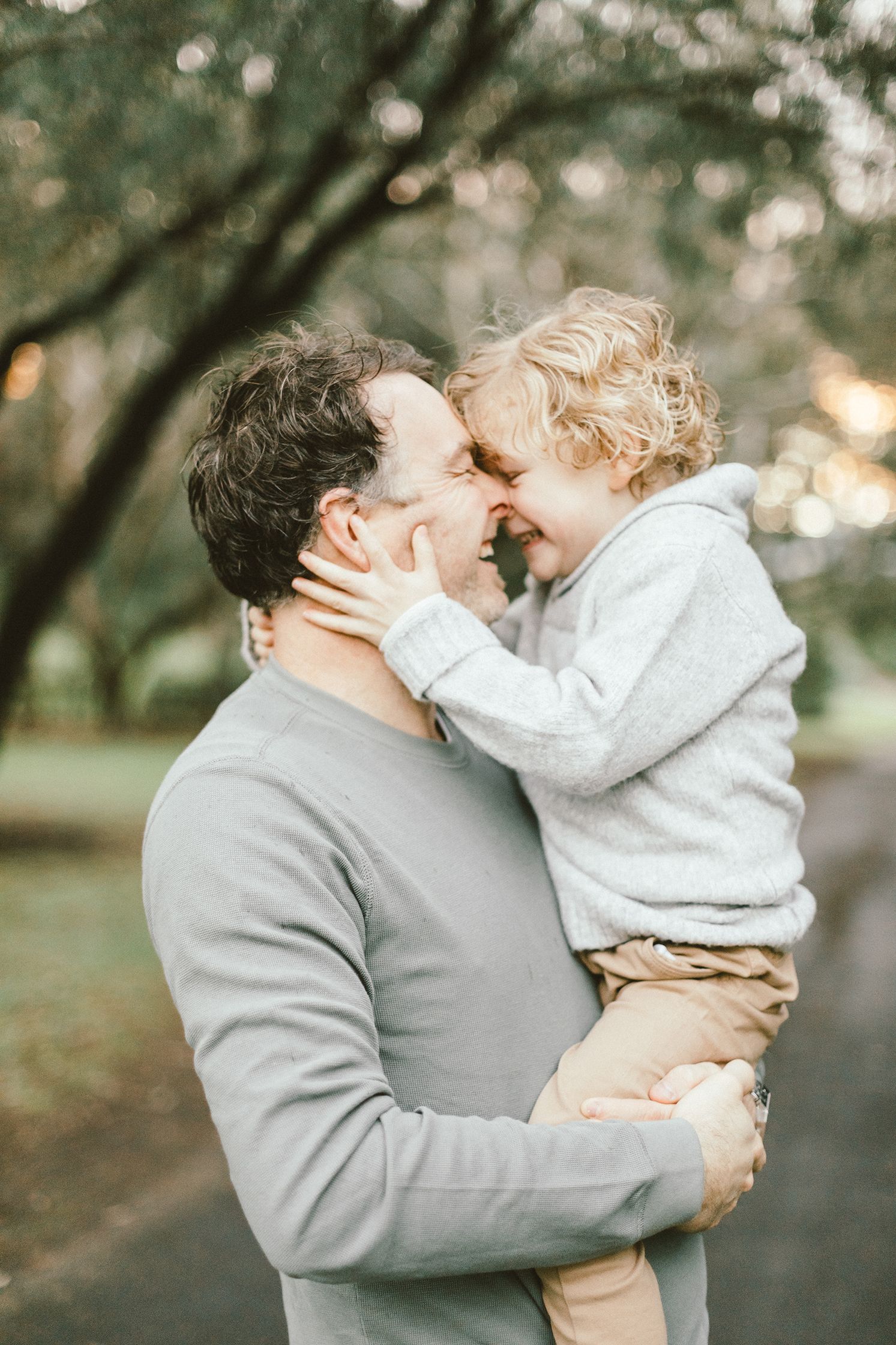 A touching nose-to-nose moment between parent and child in a park setting.