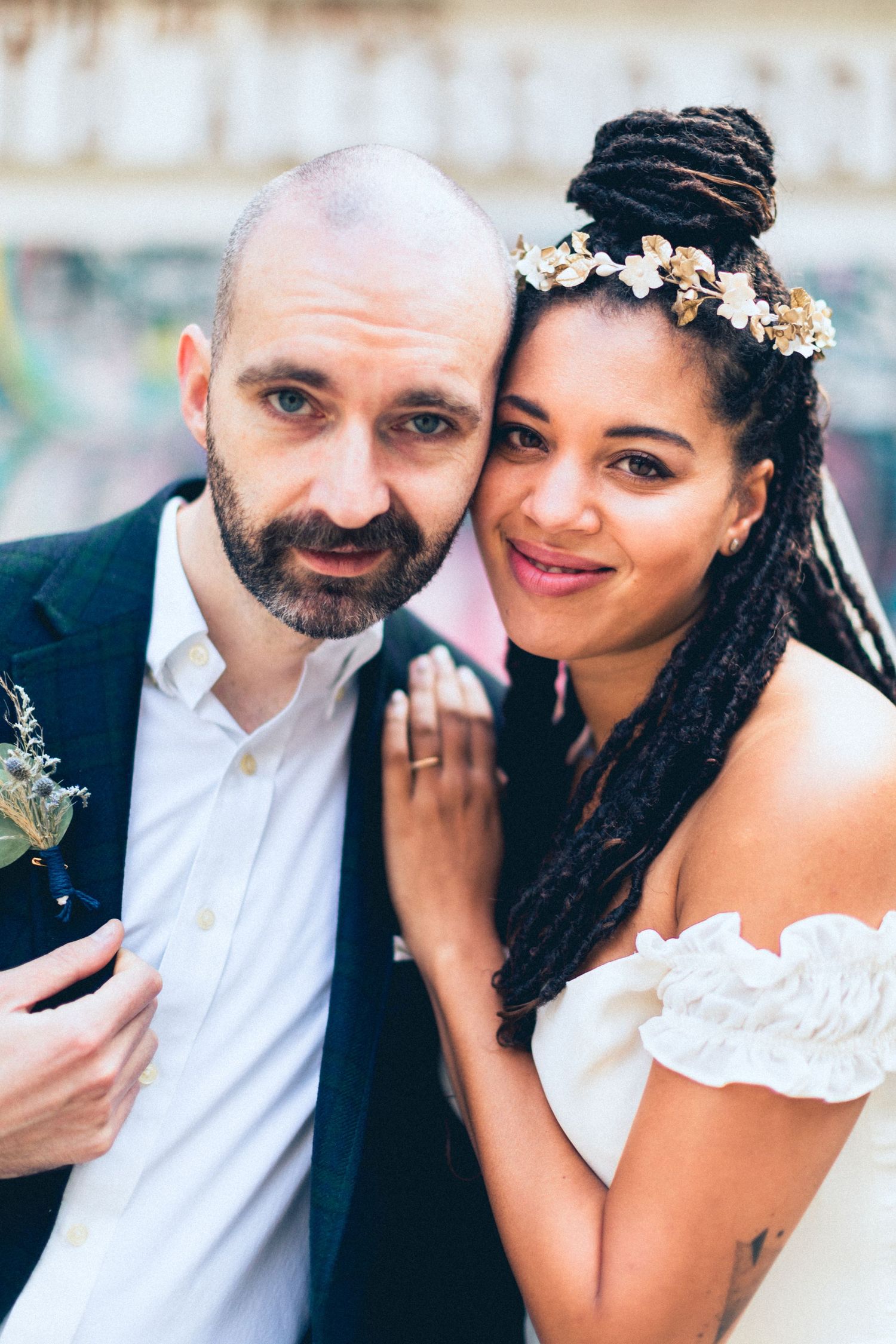 A close-up wedding portrait with the couple wearing floral accessories.