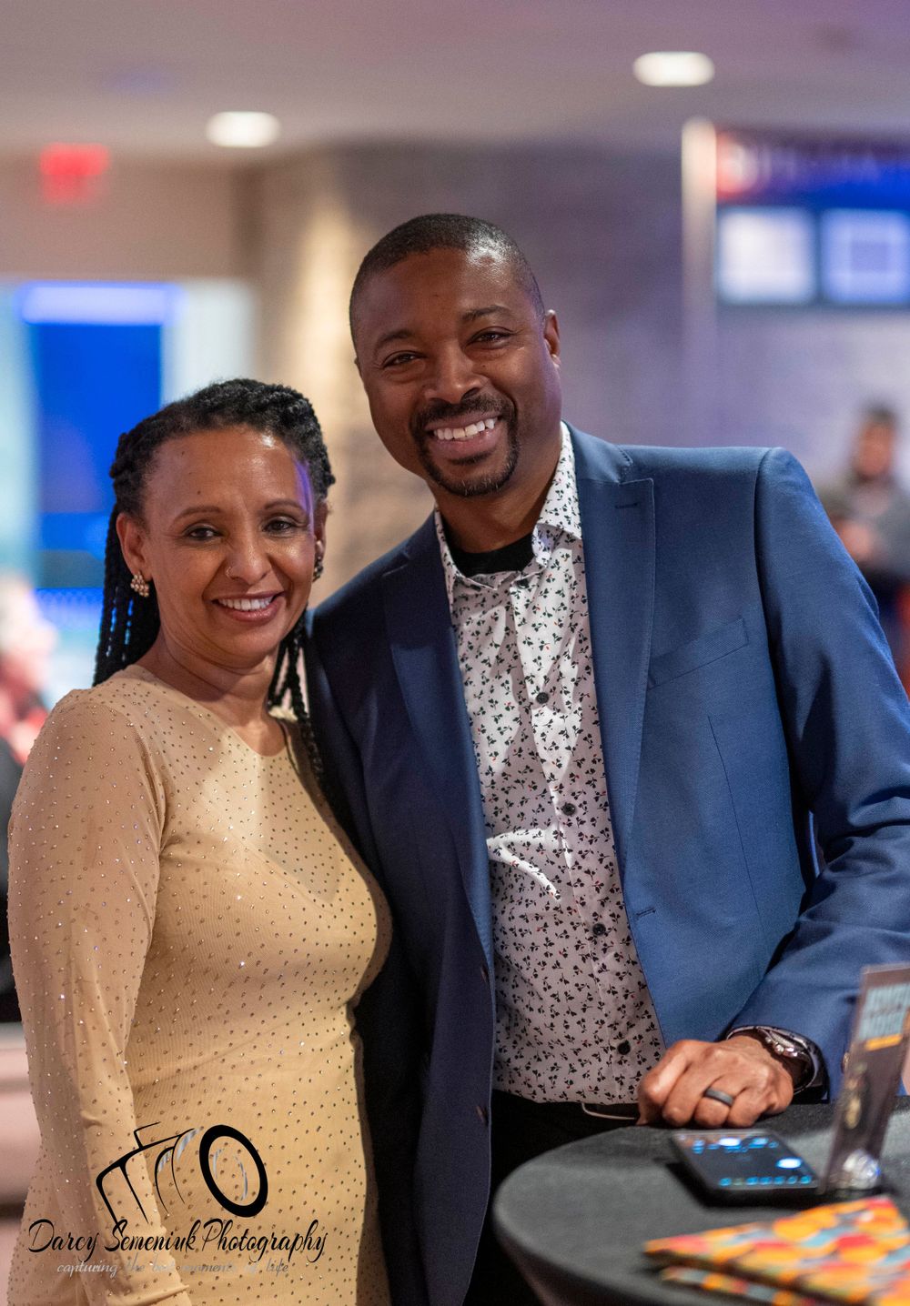 A couple in formal attire smiling together at an elegant event.
