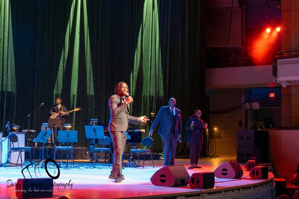 A stage performance with green lighting and theatrical equipment visible.