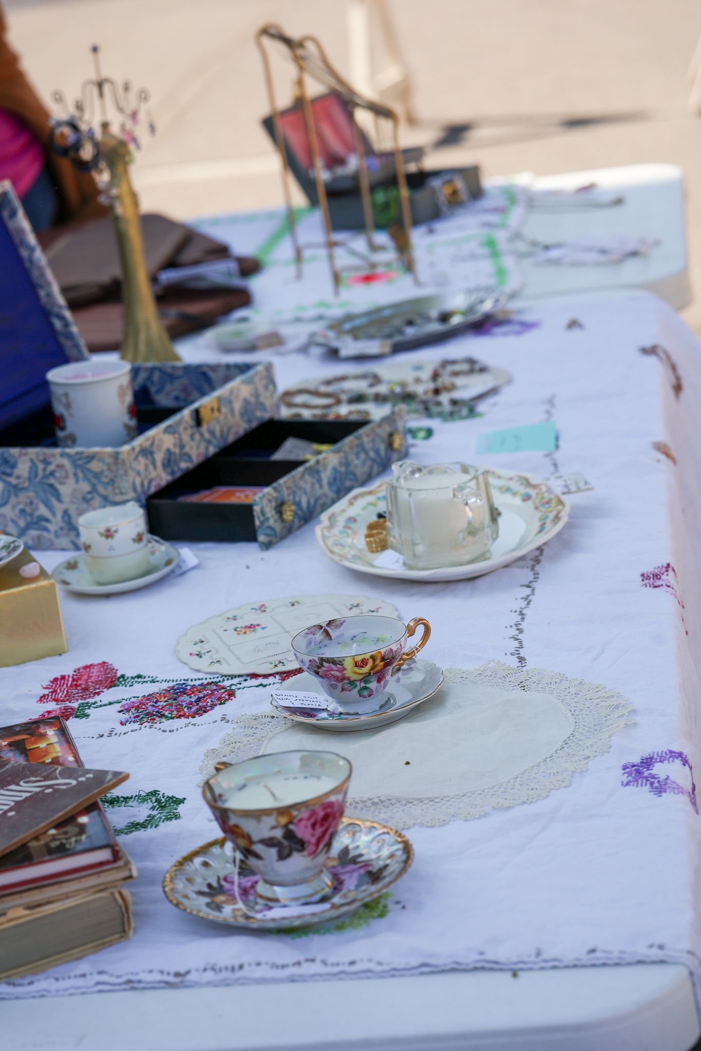 Elegant tea party setup with vintage floral teacups and white tablecloth.