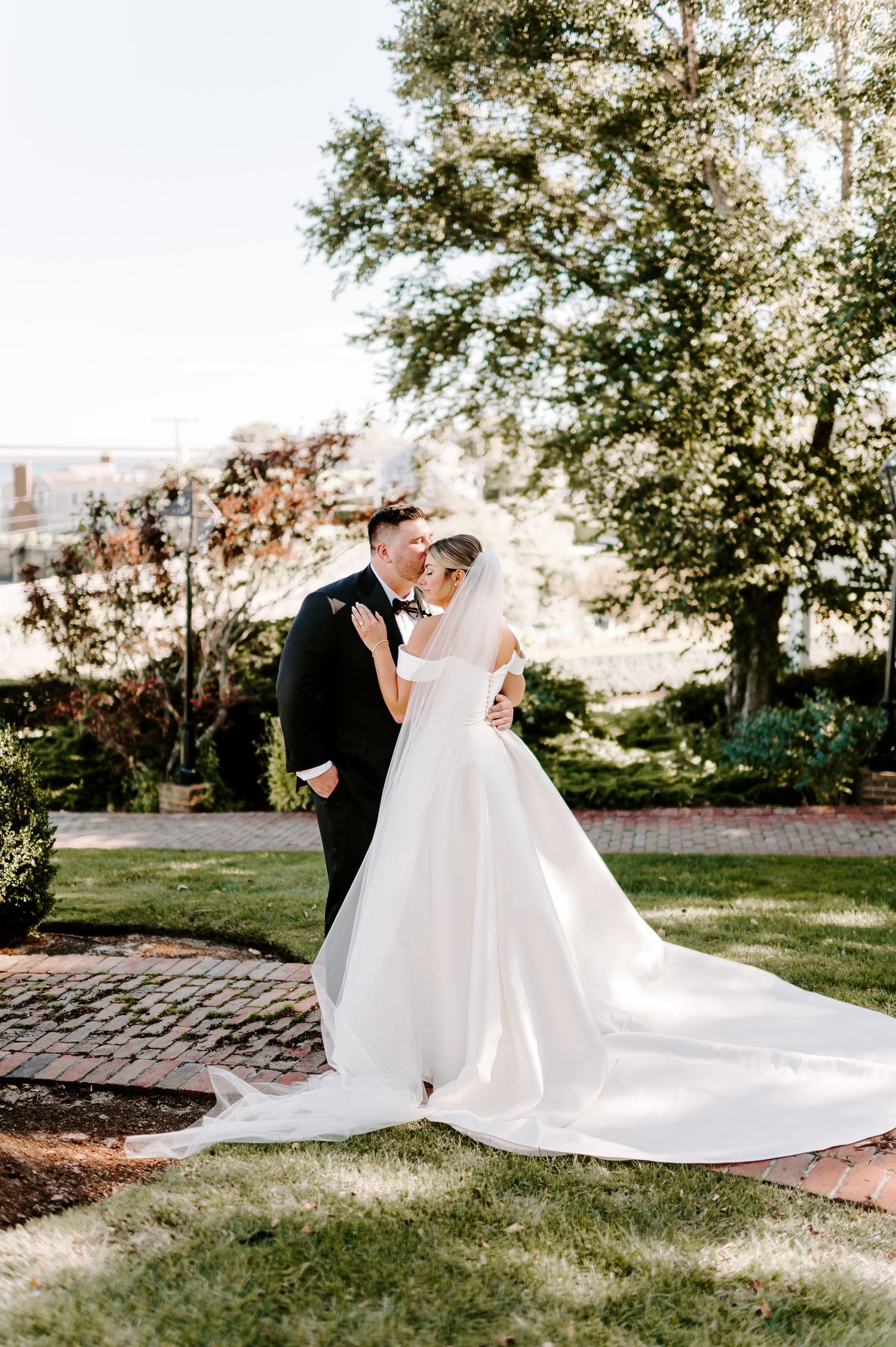 Newlyweds dance and twirl on brick pathway surrounded by trees.