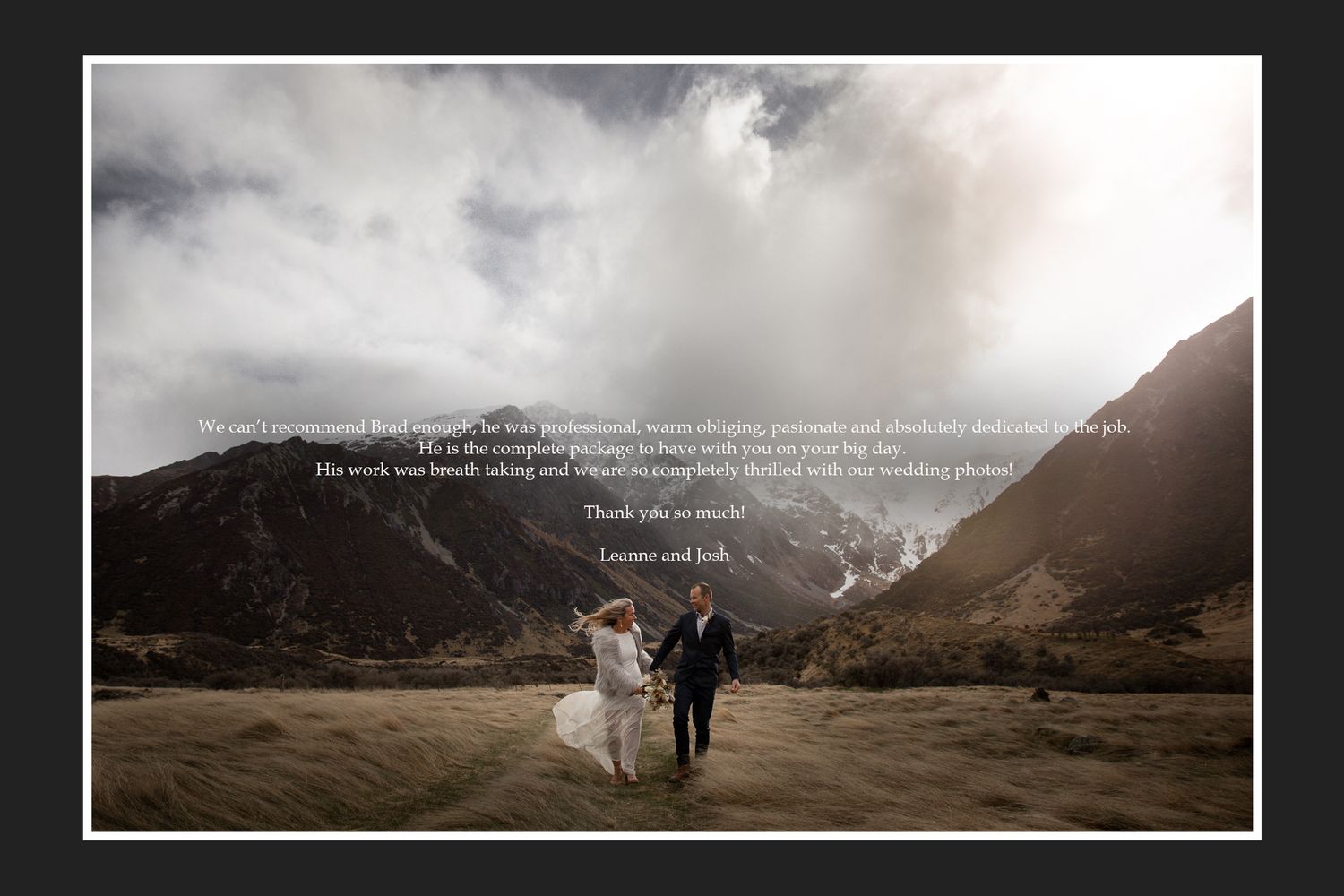 Wedding couple walking against dramatic mountain landscape with stormy clouds overhead.