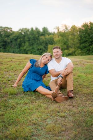 A candid moment of laughter and joy while sitting together on a grassy hillside.