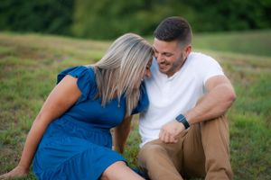 A couple sharing an intimate moment while sitting together on grassy terrain.