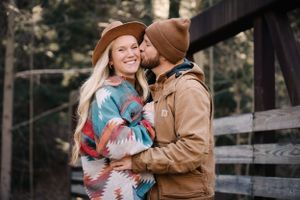 Couple sharing an intimate moment on a wooden bridge while wearing cozy winter attire.