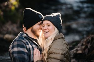 A couple in winter hats sharing a joyful moment outdoors against a natural backdrop.