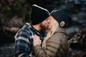 A couple sharing a tender kiss while wearing winter accessories outdoors.