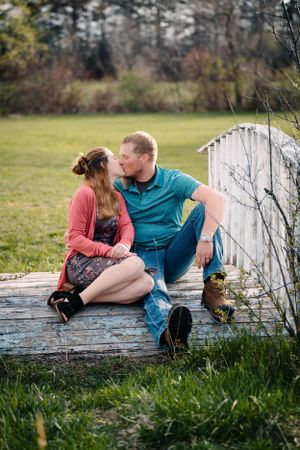 A couple sitting intimately together on a white wooden deck in a garden setting.