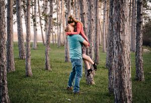A joyful couple sharing an intimate moment among tall pine trees.