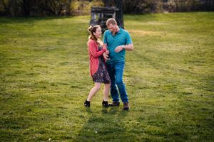 A couple dancing together on a green lawn during a romantic outdoor photoshoot.
