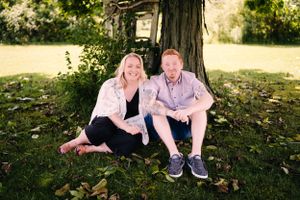 Couple relaxing together under large tree in sunny garden setting.
