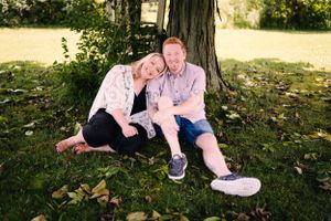 Happy couple sharing intimate moment while sitting under tree in park.
