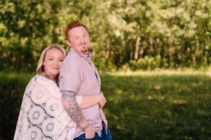 A couple shares a joyful embrace while posing outdoors against a natural backdrop.