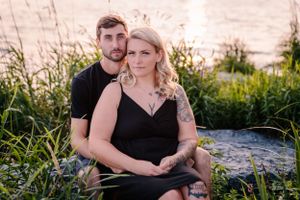 An intimate portrait of two people sitting together by the water as sunset approaches.
