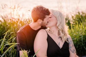 Intimate sunset moment captured between couple among waterfront reeds.